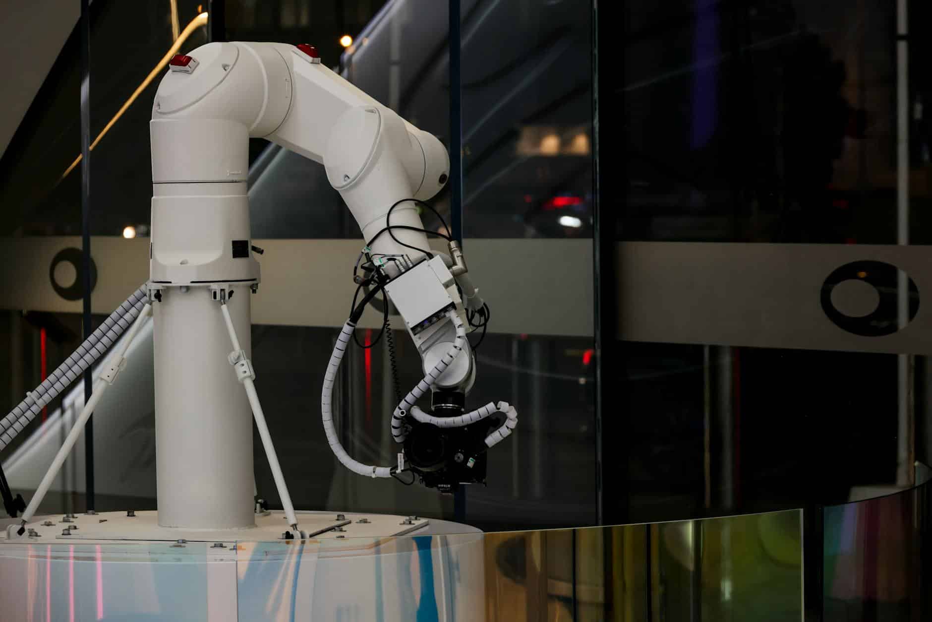 White industrial robotic arm with connected cables in a modern interior setting.