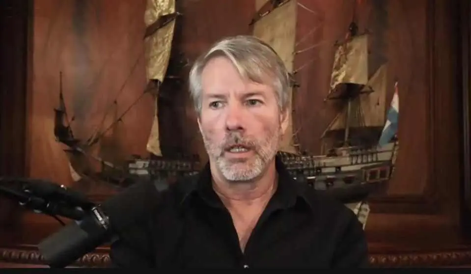 Michael Saylor speaking in front of a model ship and wooden paneling.