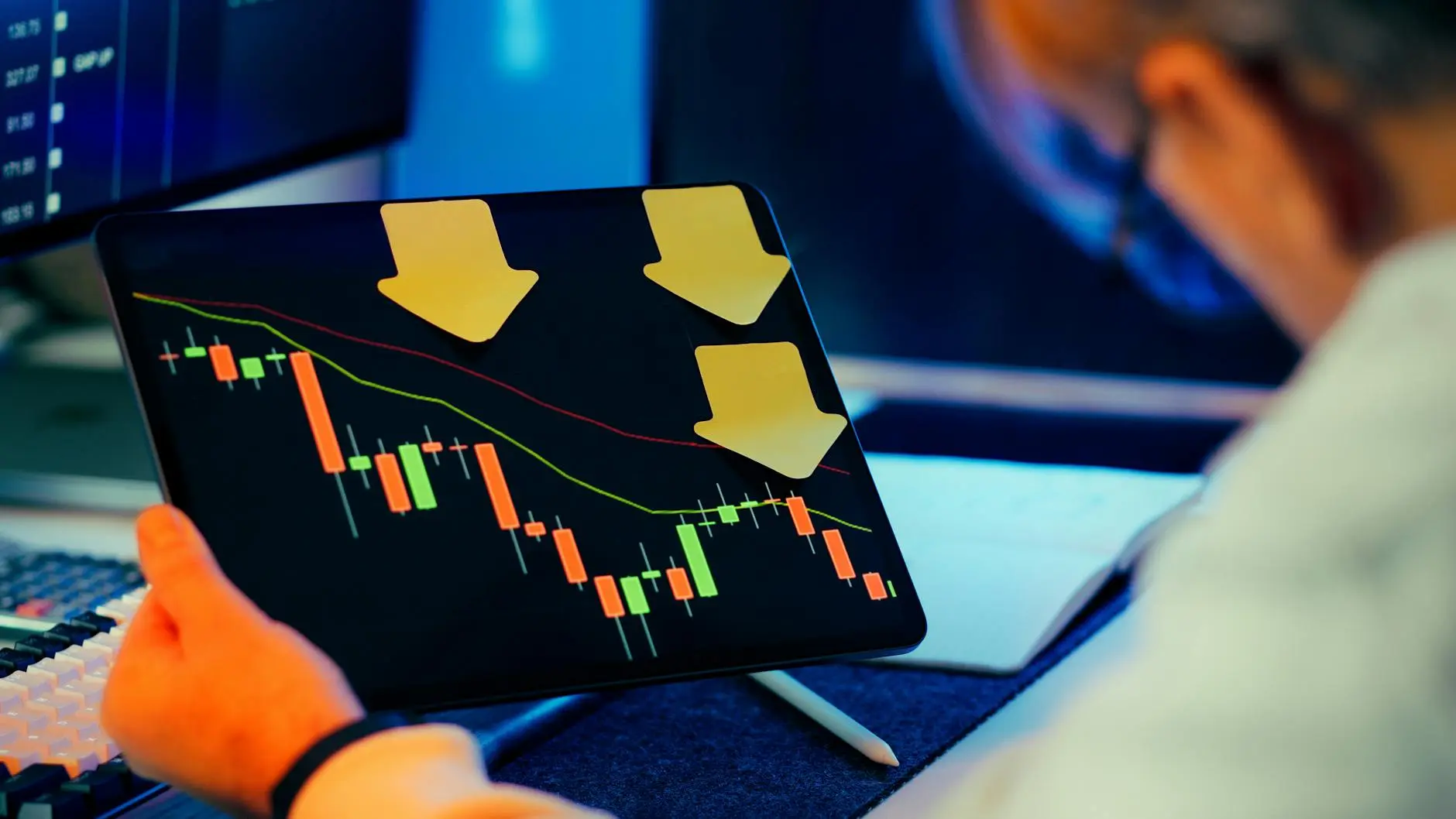 Person analyzing a downward trending Bitcoin chart on a tablet with arrows indicating loss.