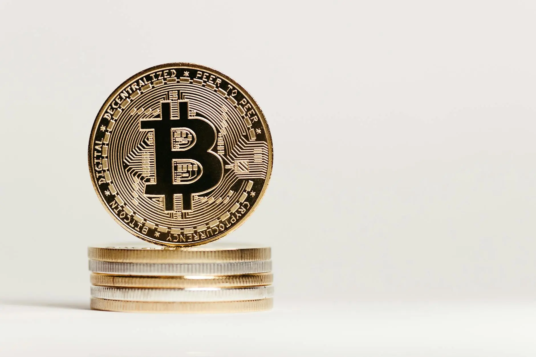 A stack of Bitcoin coins with one prominently displayed in front.
