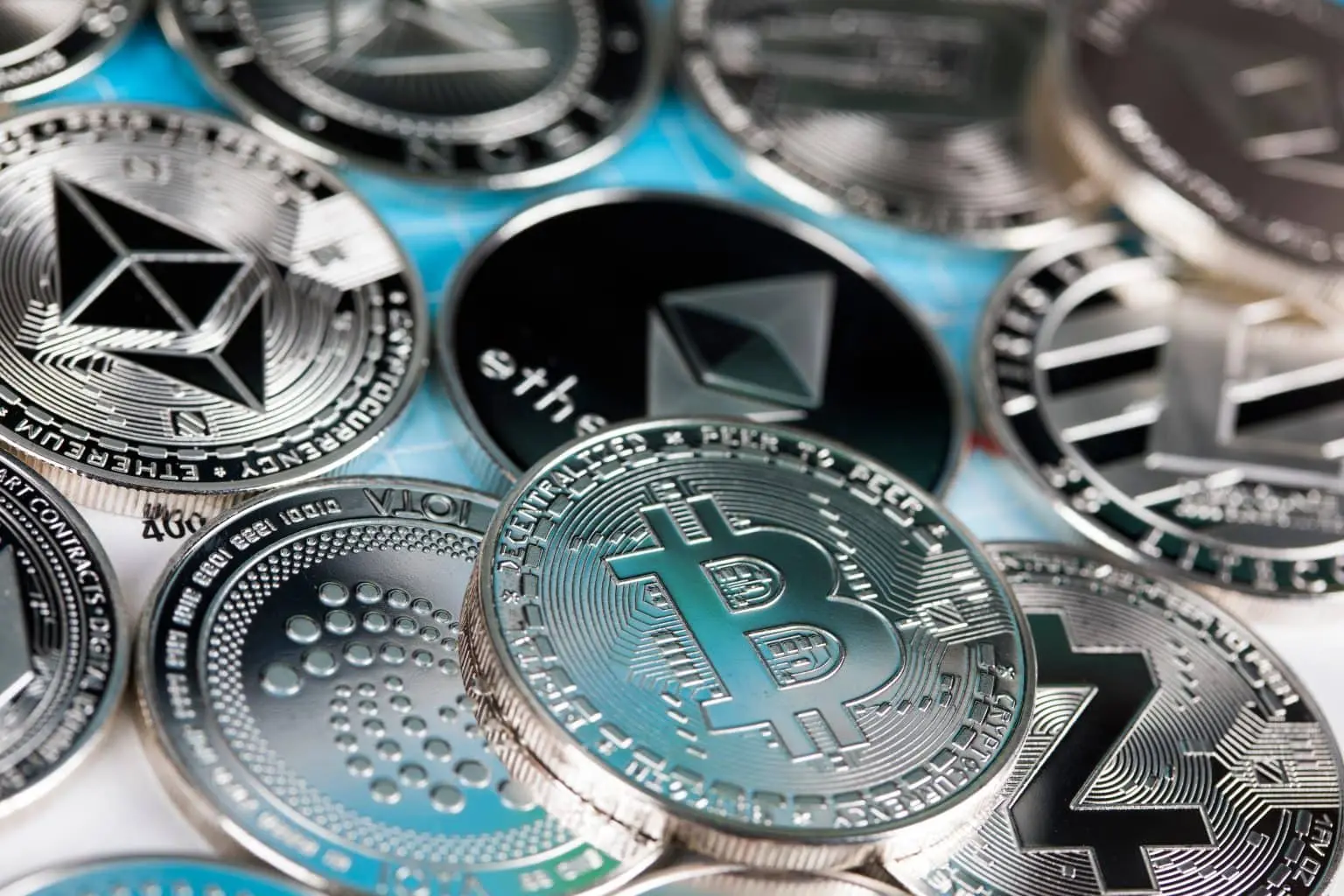 A close-up of various cryptocurrency coins including Bitcoin and Ethereum on a surface.