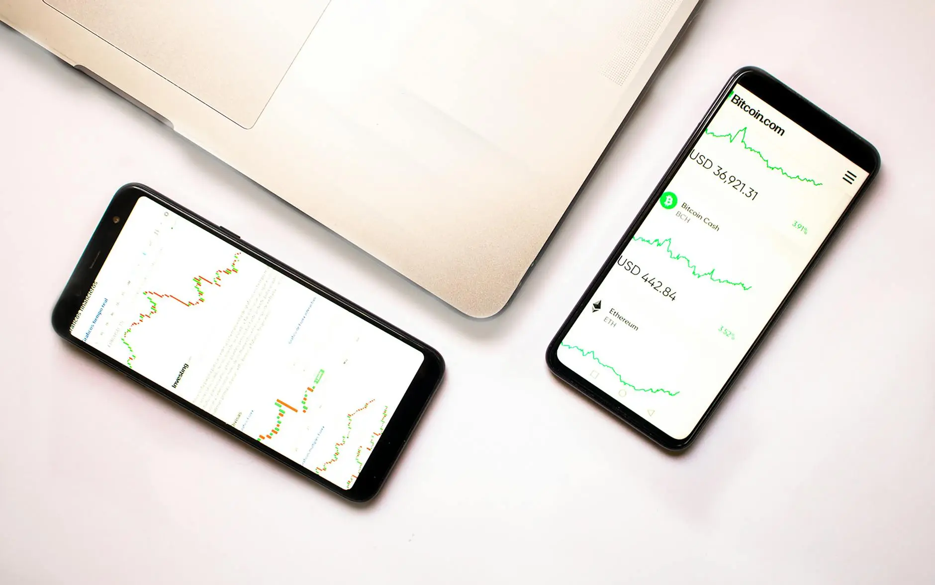 Two mobile phones displaying cryptocurrency price charts on a white surface.