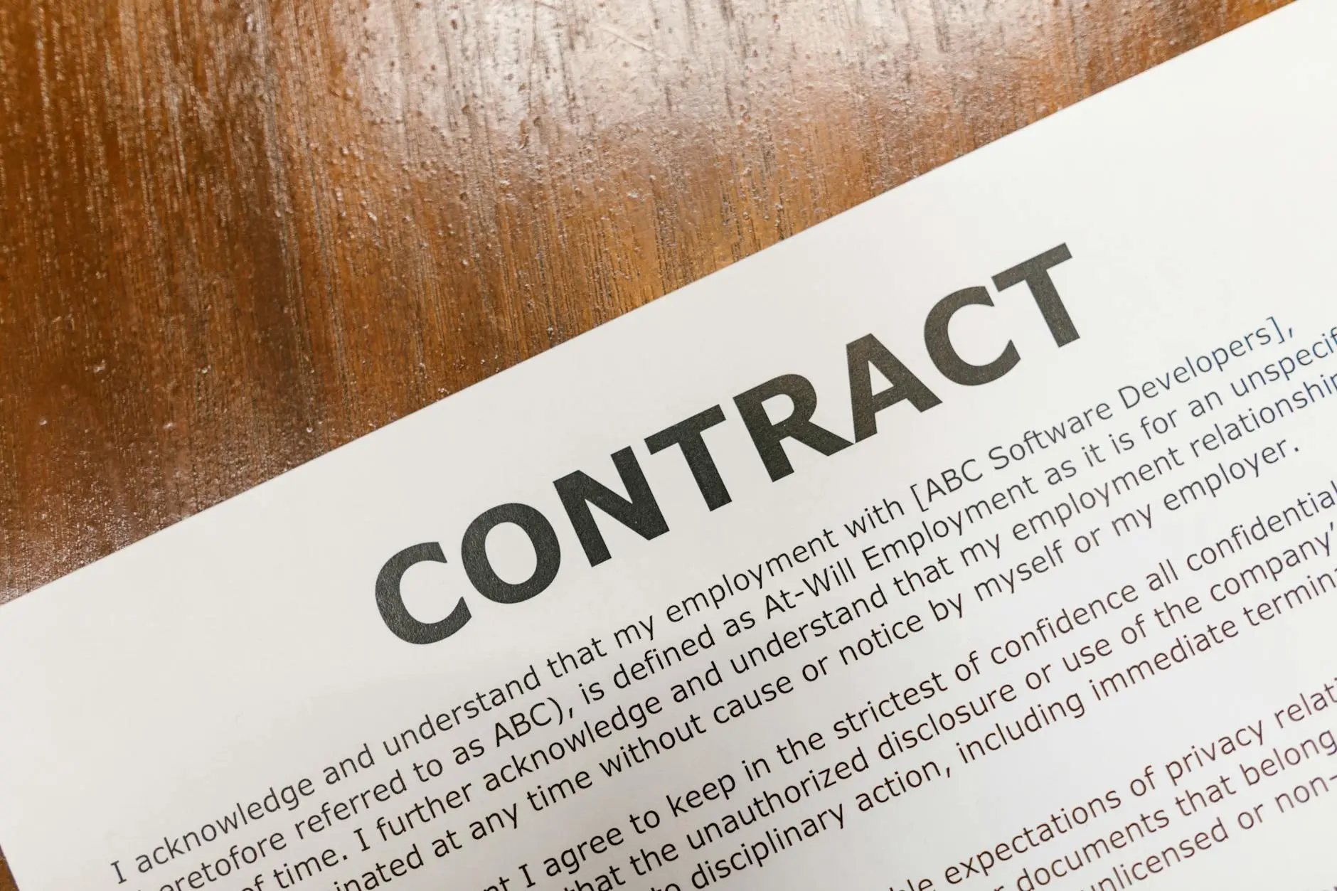 Close-up of a printed employment contract on a wooden surface.