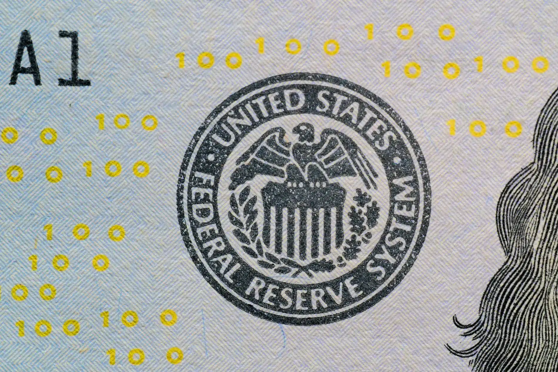 Close-up of a Federal Reserve System seal on a banknote with blue and yellow patterns.