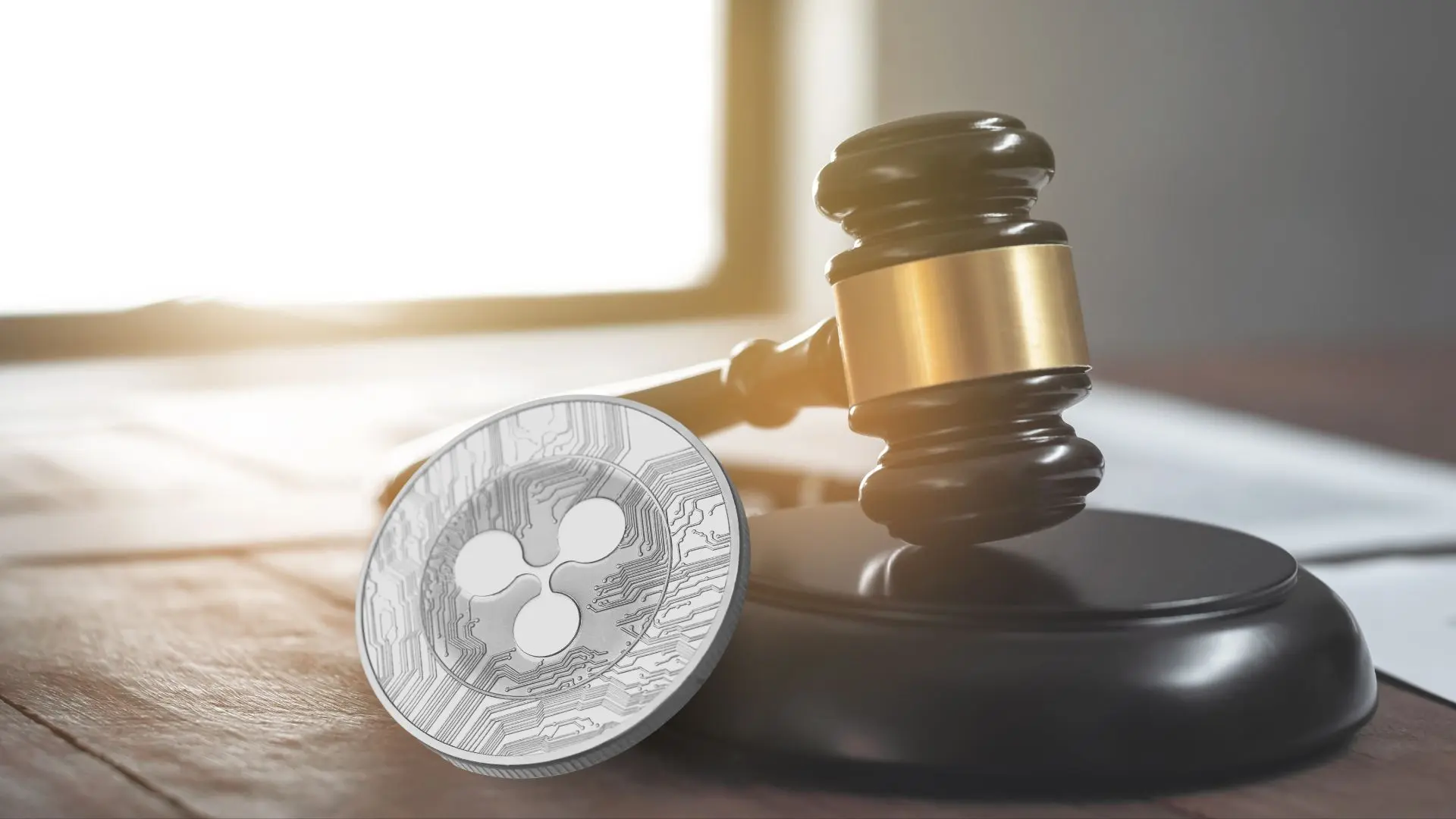 A gavel and a cryptocurrency coin representing Ripple on a wooden desk.