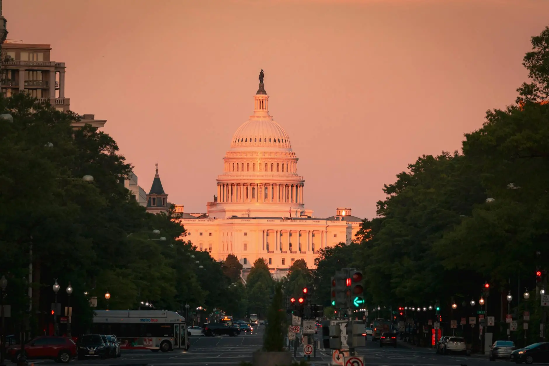 The US Capitol Building at dusk with a soft orange sky.