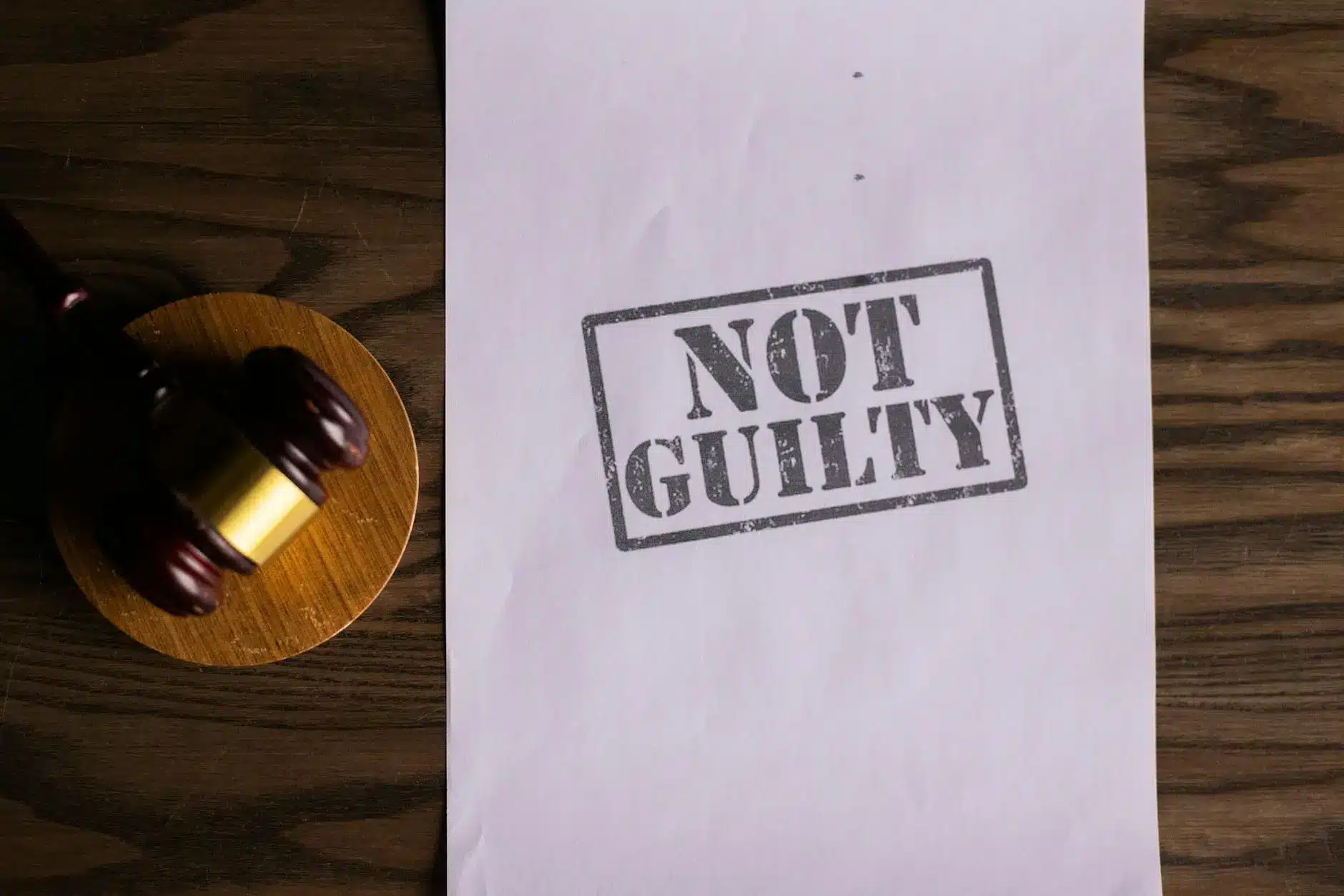 A gavel and a document stamped with 'NOT GUILTY' on a wooden surface.