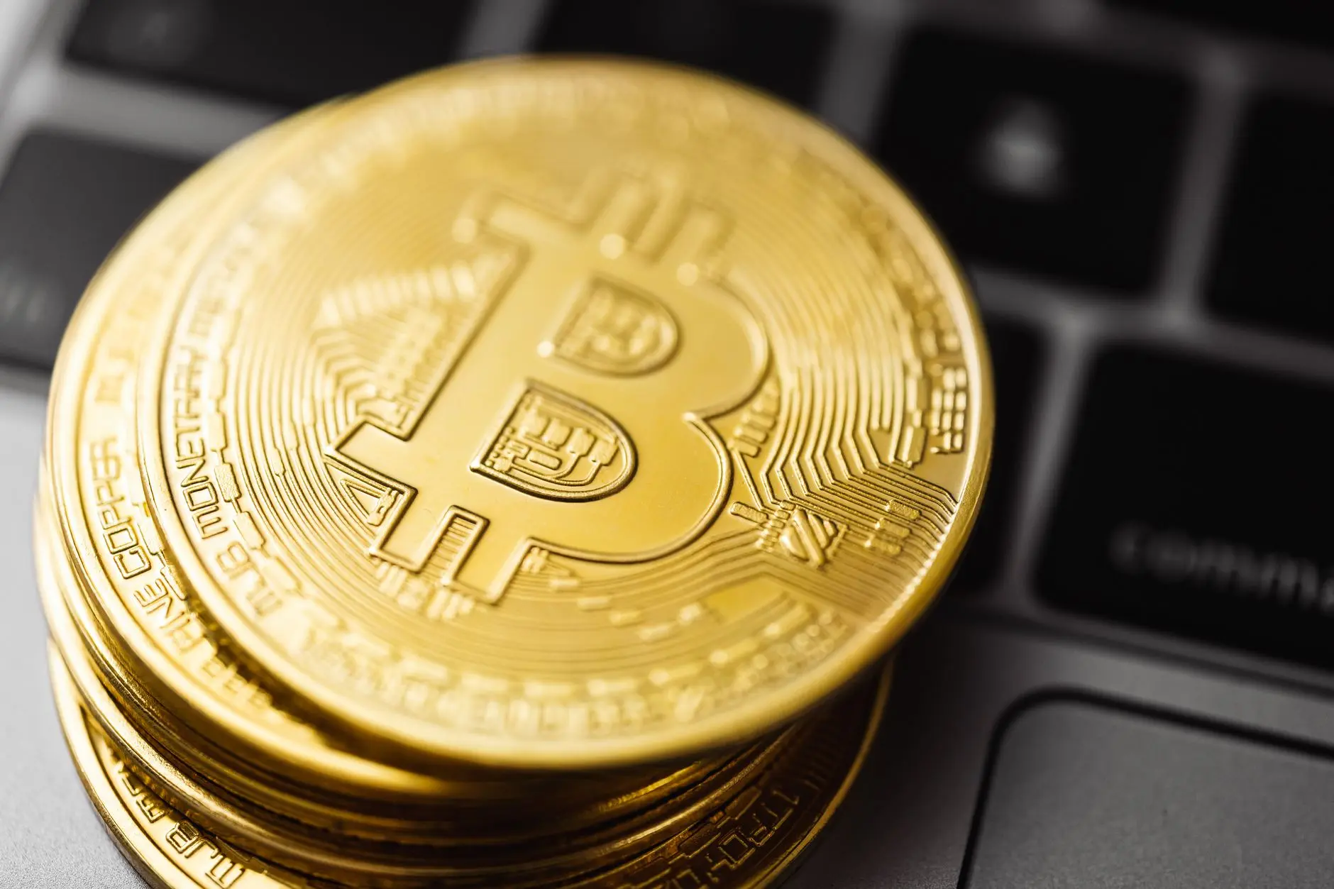 Close-up of gold Bitcoin coins on a laptop keyboard.