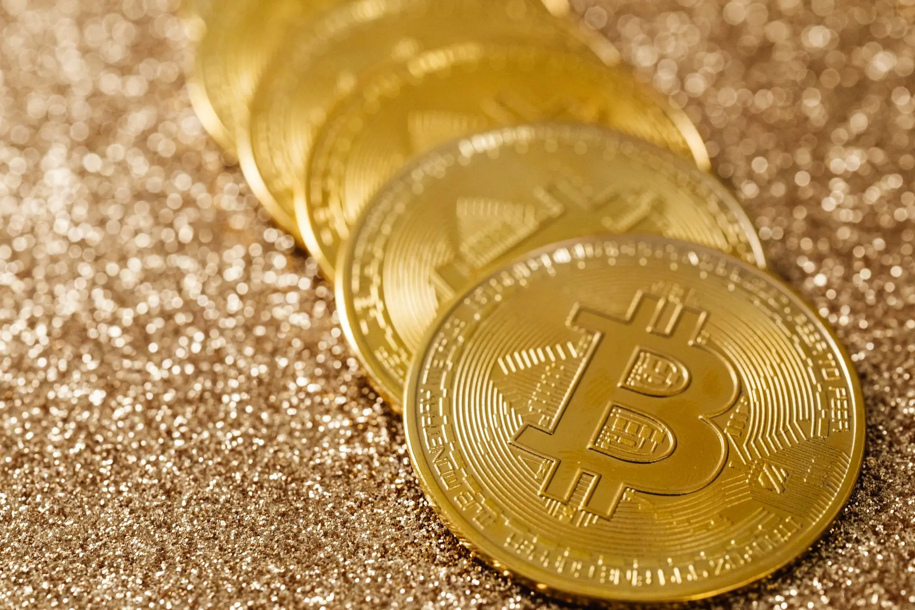 Gold Bitcoin coins arranged on a sparkling surface.