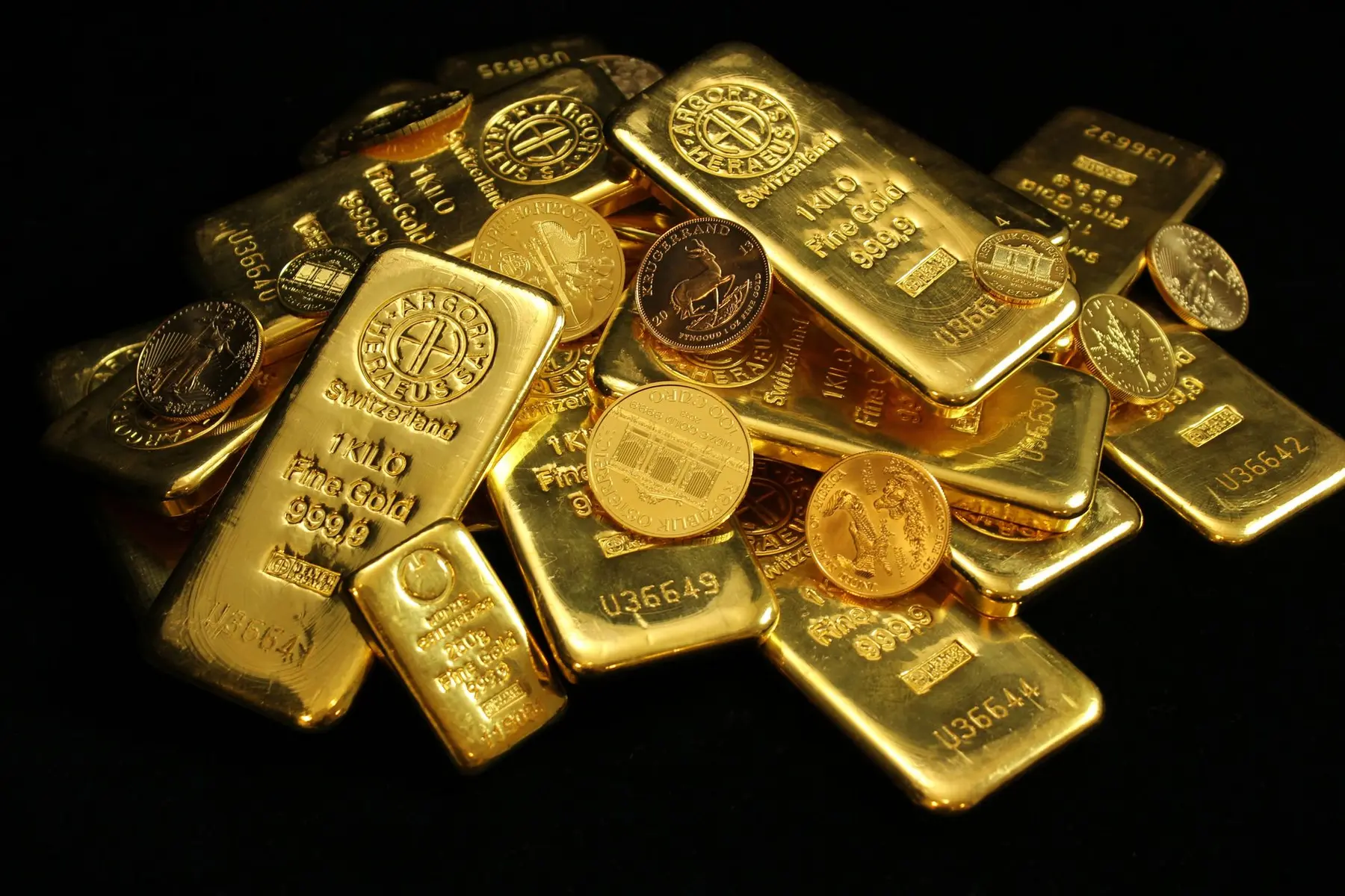 A collection of gold bullion bars and coins stacked together.