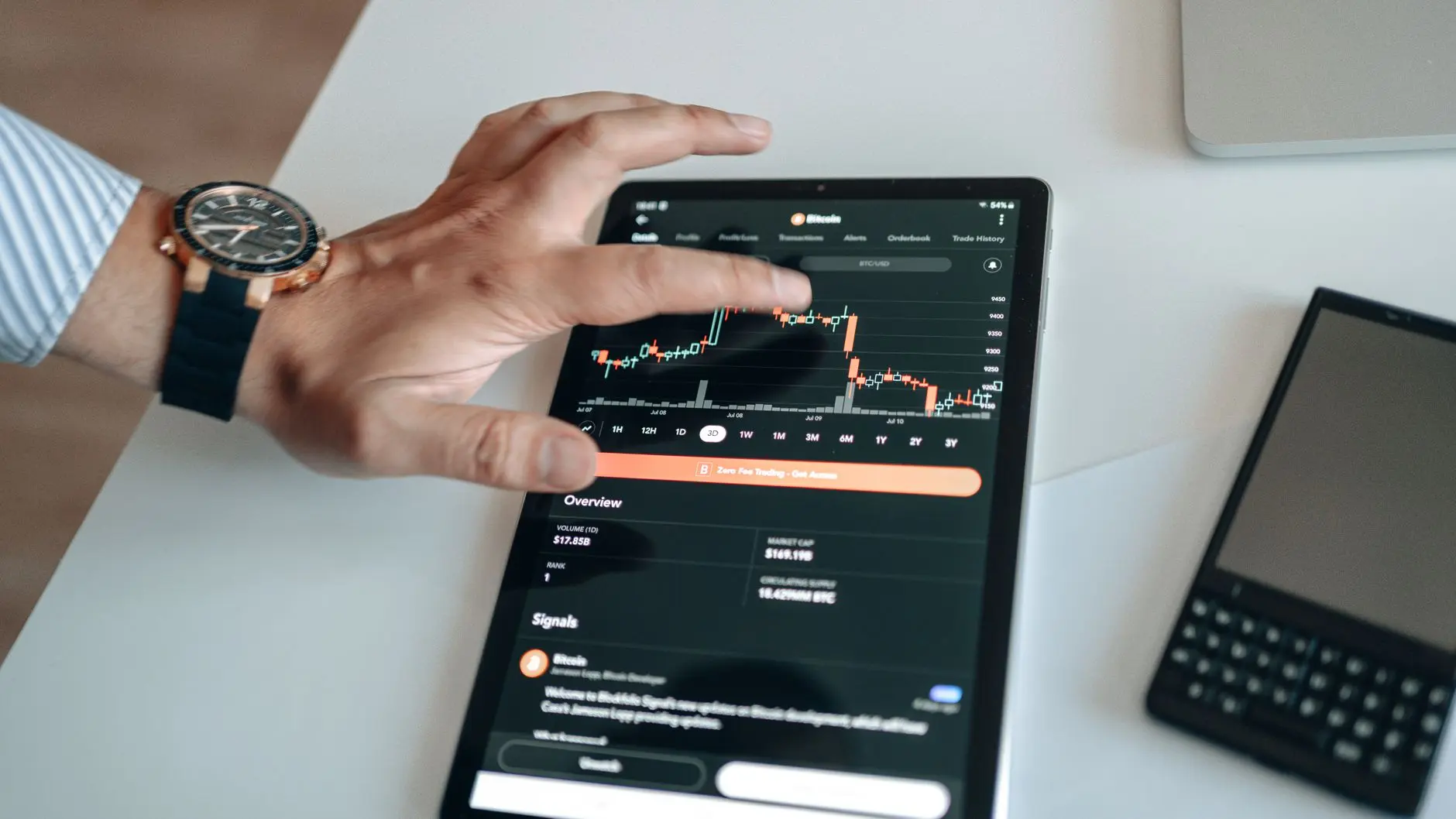 Close-up of a hand interacting with a financial trading app on a tablet, showing stock charts.