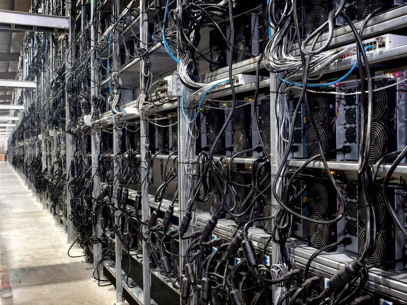 Rows of industrial server racks filled with cryptocurrency mining hardware and complex cabling
