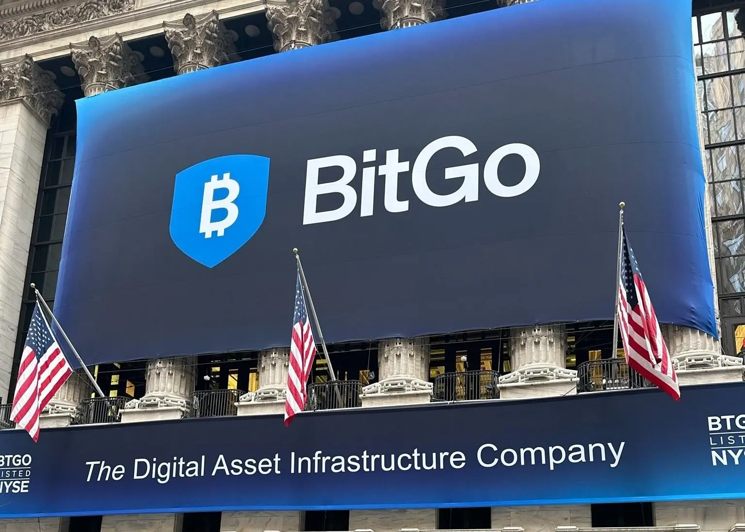 Large BitGo banner displayed on the facade of the New York Stock Exchange with American flags.