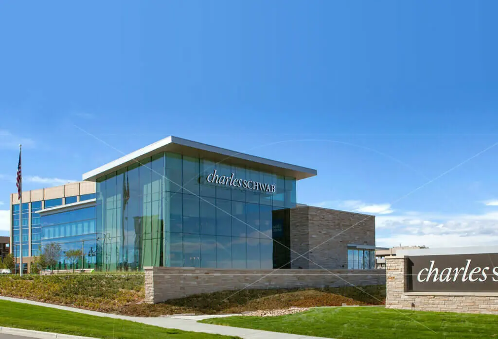Modern glass and stone Charles Schwab corporate building with company signage under a clear blue sky