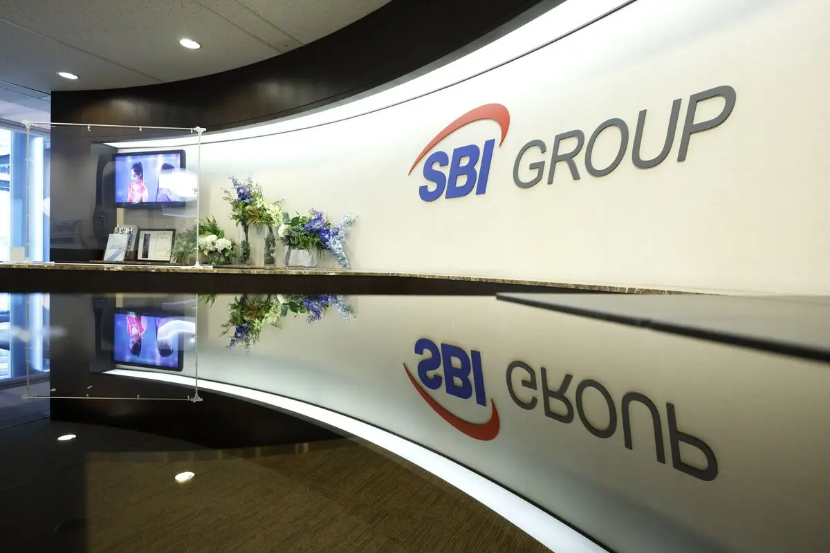 SBI Group logo on a curved white wall behind a reflective reception desk with flowers and a TV screen