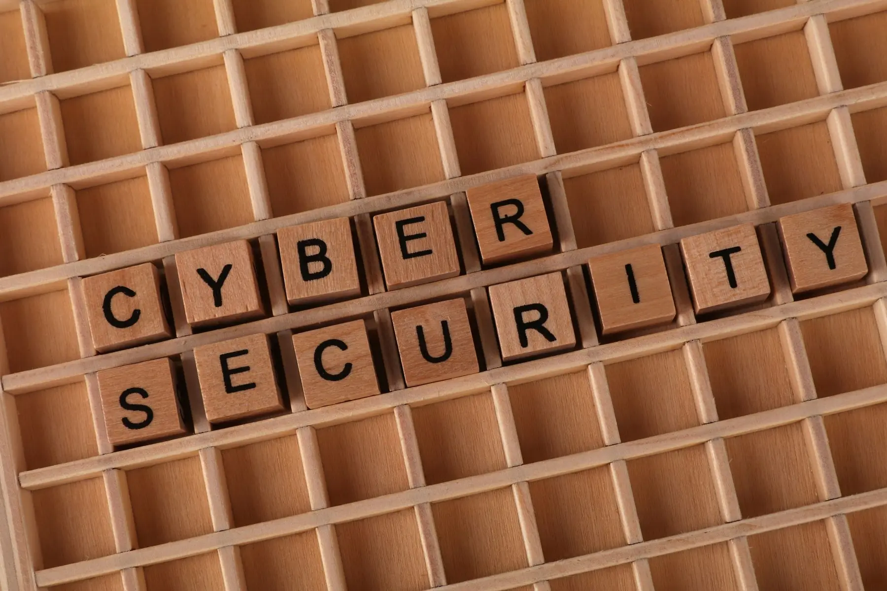 Wooden blocks spelling 'CYBER SECURITY' arranged in a wooden grid tray