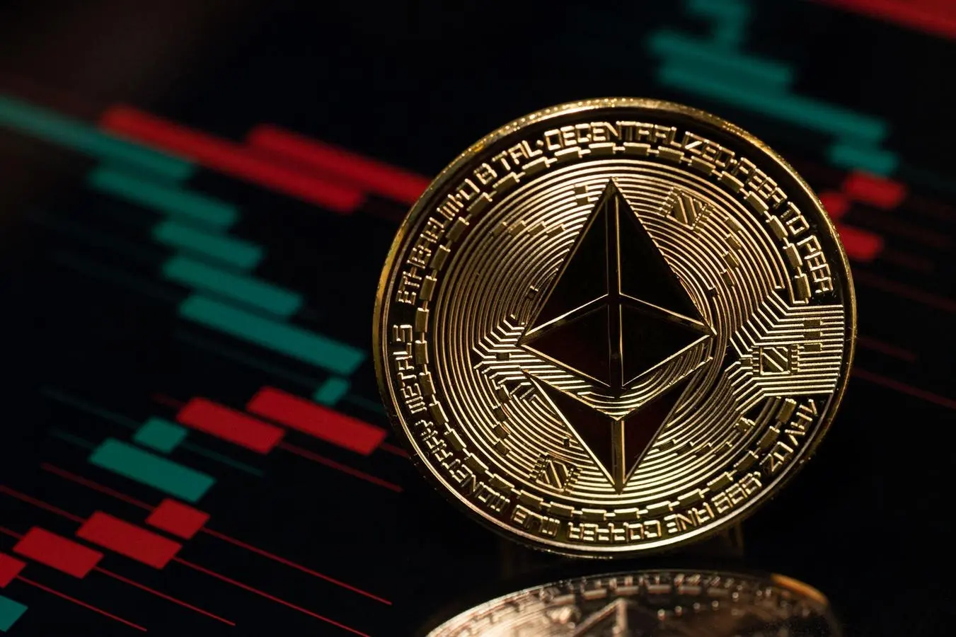 A gold Ethereum token featuring the diamond-shaped logo in front of a blurred red and green financial candle chart
