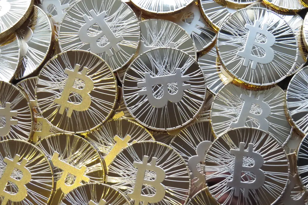 Nahaufnahme mehrerer goldfarbener physischer Bitcoin-Münzen mit dem Bitcoin-Symbol.