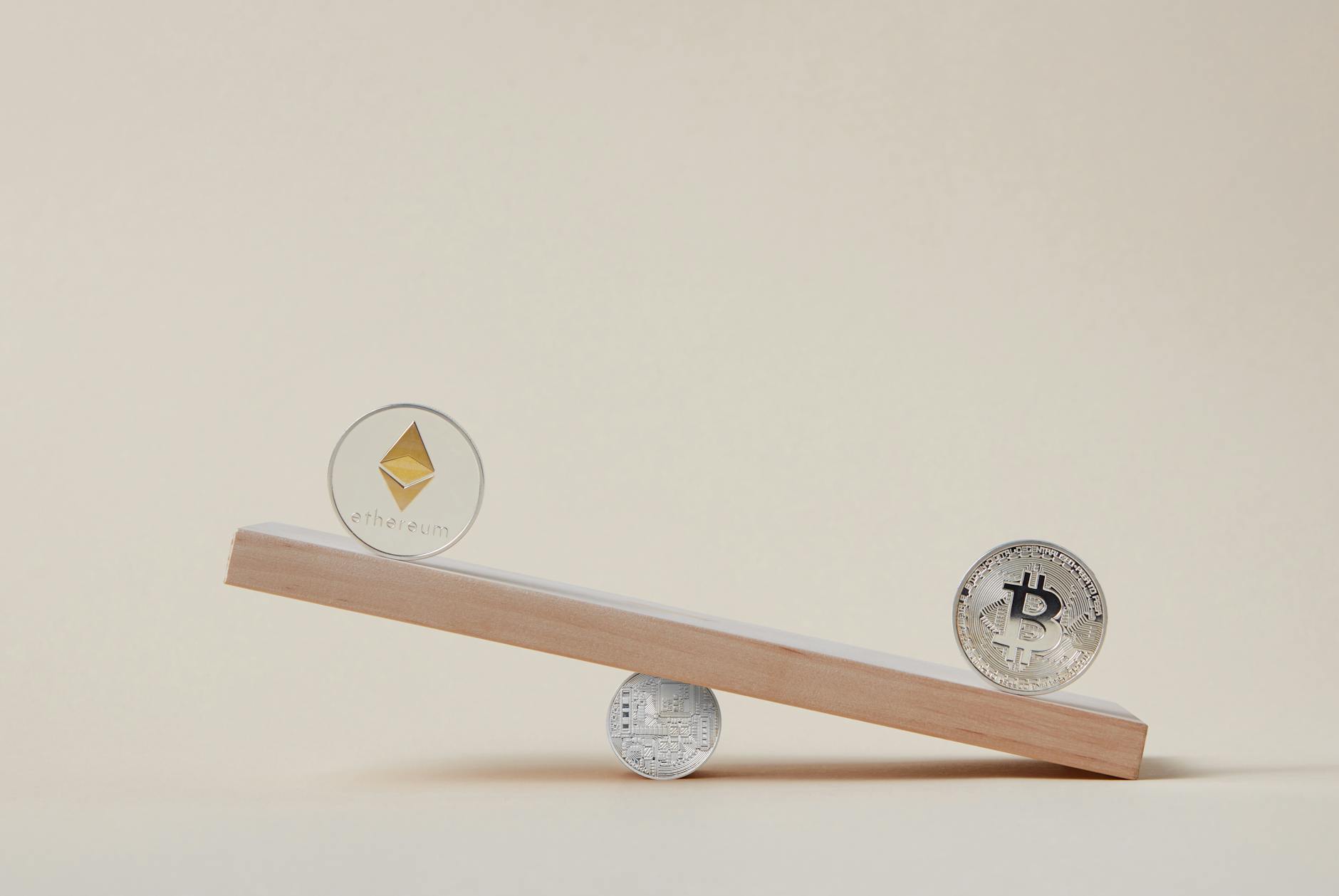 Ethereum and Bitcoin coins on a wooden seesaw in balance.