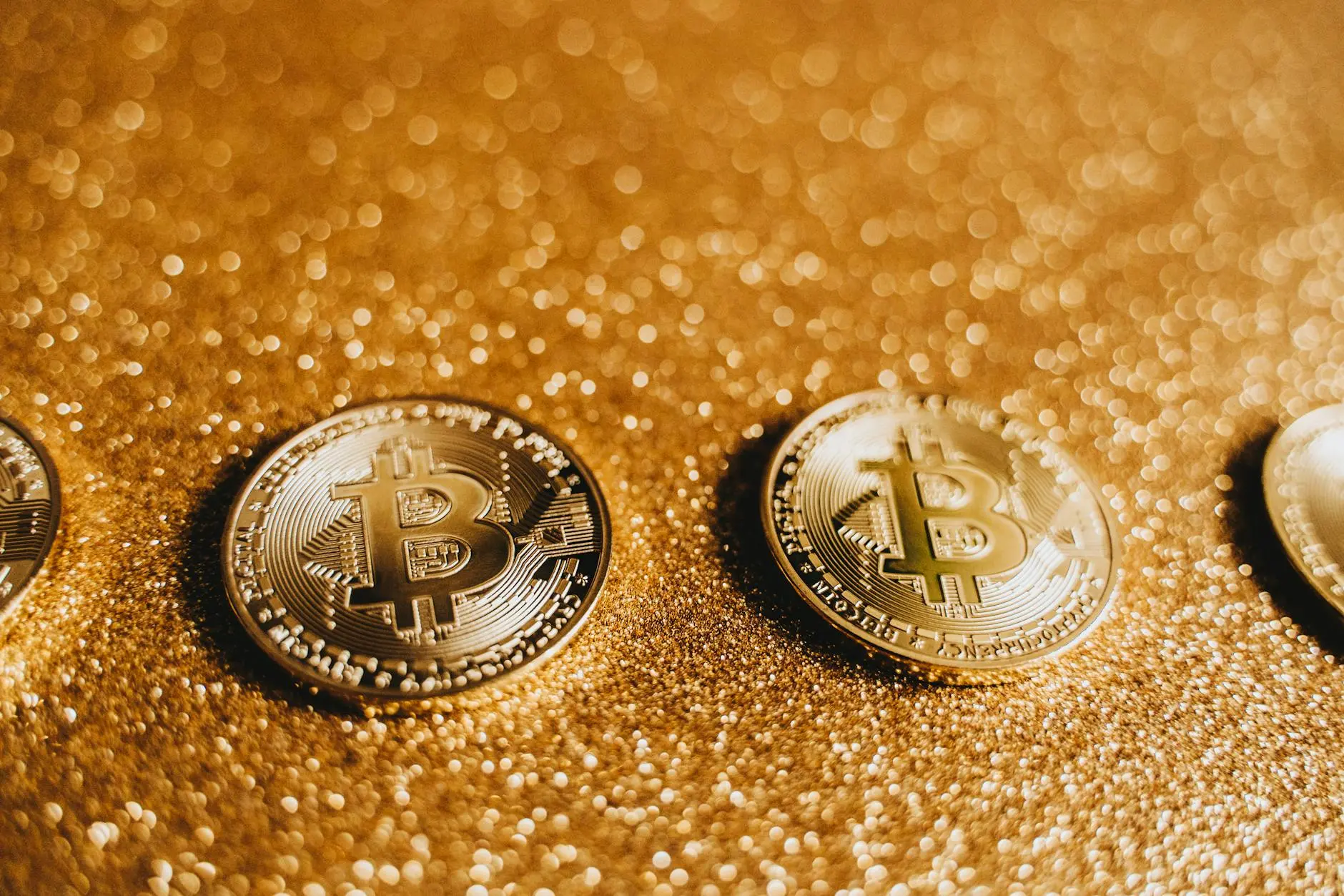 Close-up of shiny Bitcoin coins on a glittery gold background.