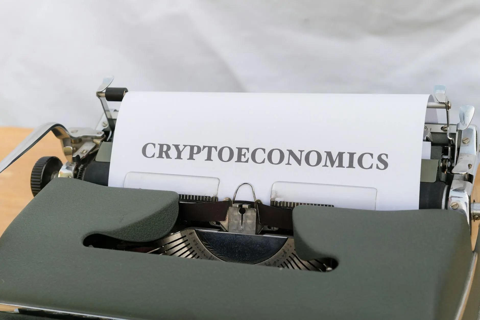 A typewriter with a sheet of paper displaying the word 'CRYPTOECONOMICS'.