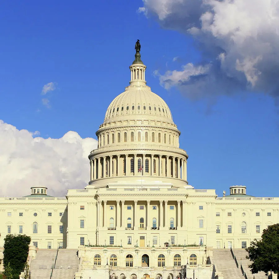 The US Capitol building in Washington DC under a blue sky with clouds.