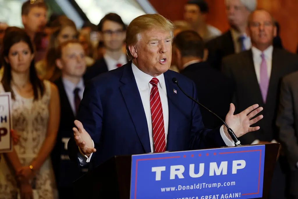 Donald Trump spreekt het publiek toe achter een katheder met zijn naam erop.