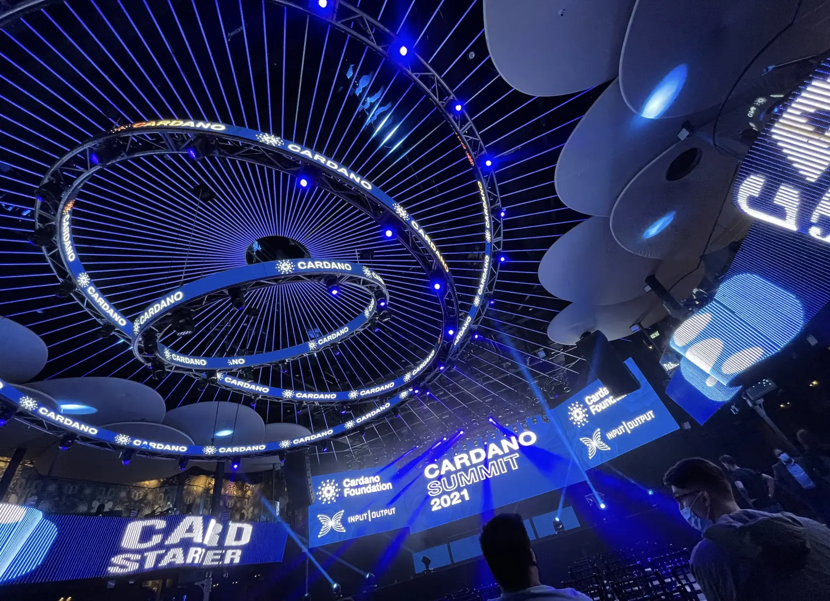 Interieur van de Cardano Summit 2021 met blauwe verlichting en Cardano Foundation branding.