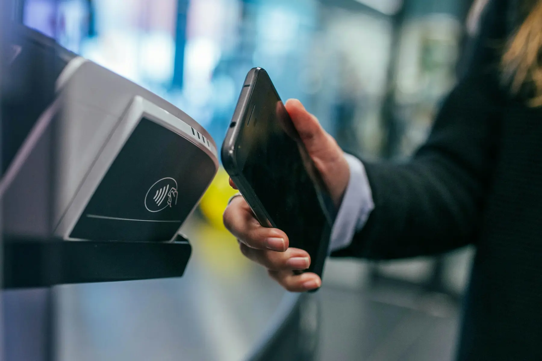 Een persoon die een smartphone gebruikt voor een contactloze betaling bij een betaalterminal.