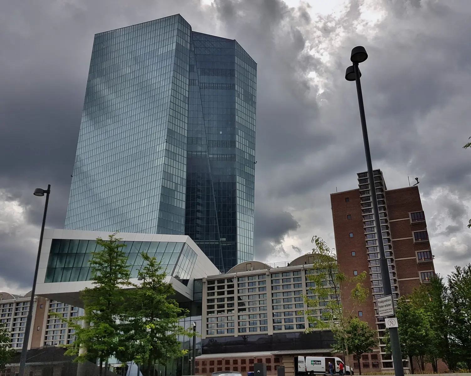 Het glazen hoofdkantoor van de Europese Centrale Bank in Frankfurt onder een bewolkte lucht.