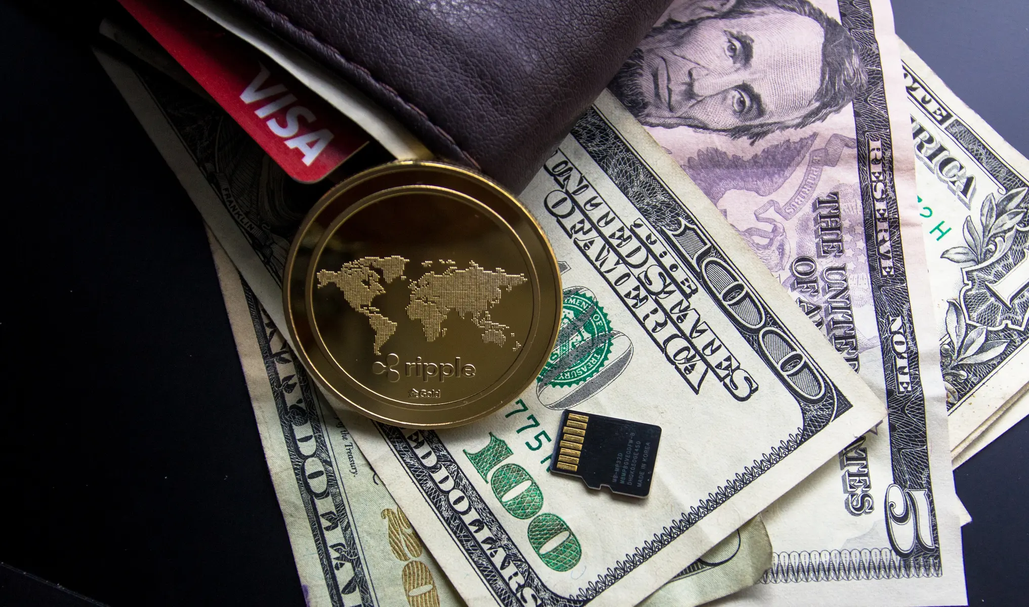 Een gouden Ripple (XRP) munt op Amerikaanse dollars, een portemonnee en een SD-kaart.