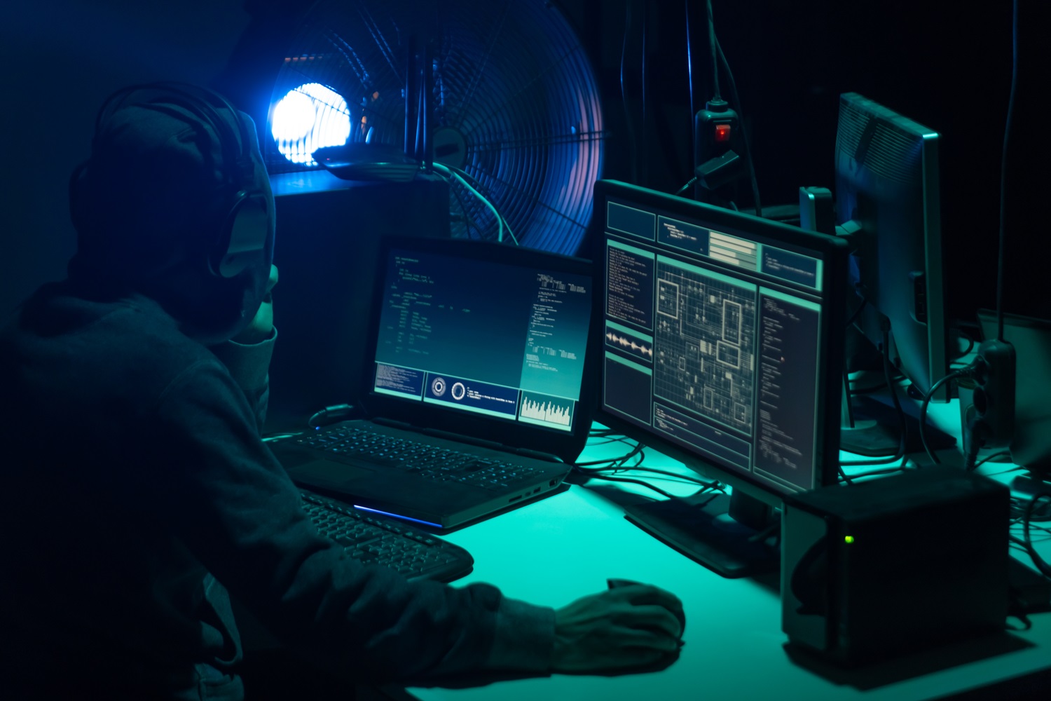 A group of people uses computers in a dark room.