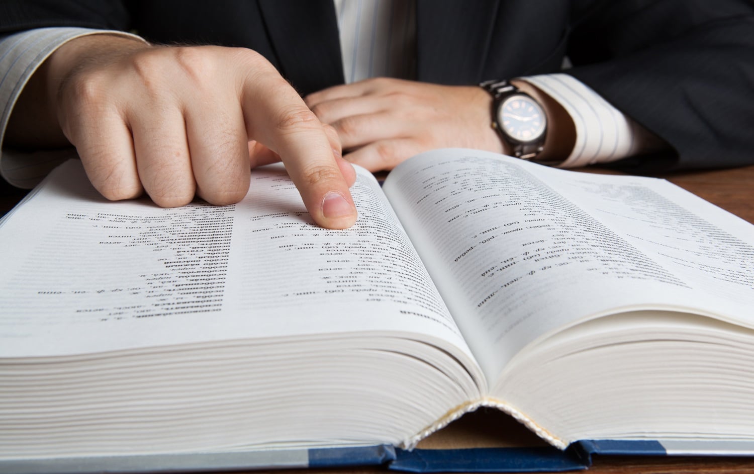 A man in a suit searches for a term in a large paper glossary.