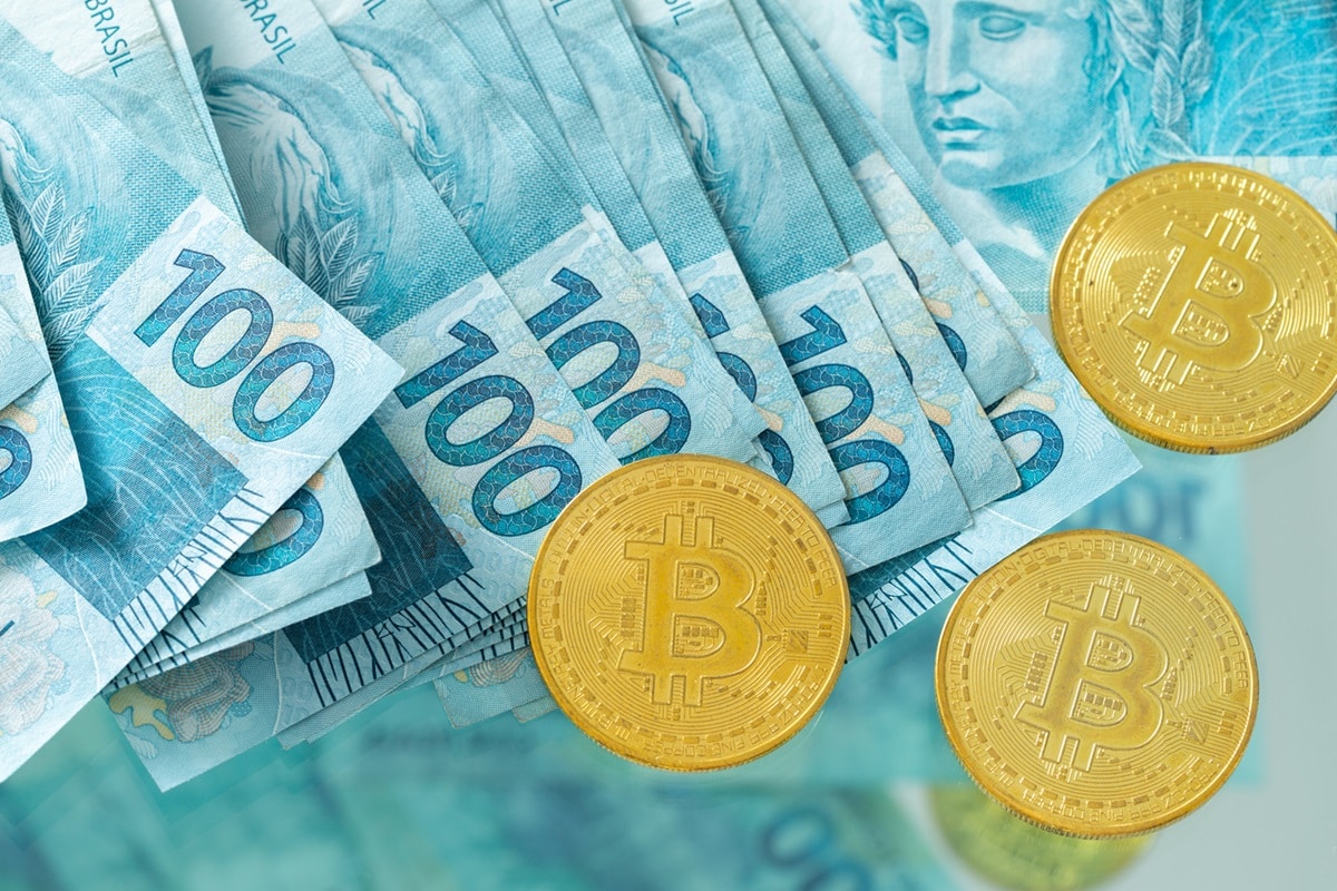 A selection of Brazilian banknotes and metal coins intended to represent Bitcoin.