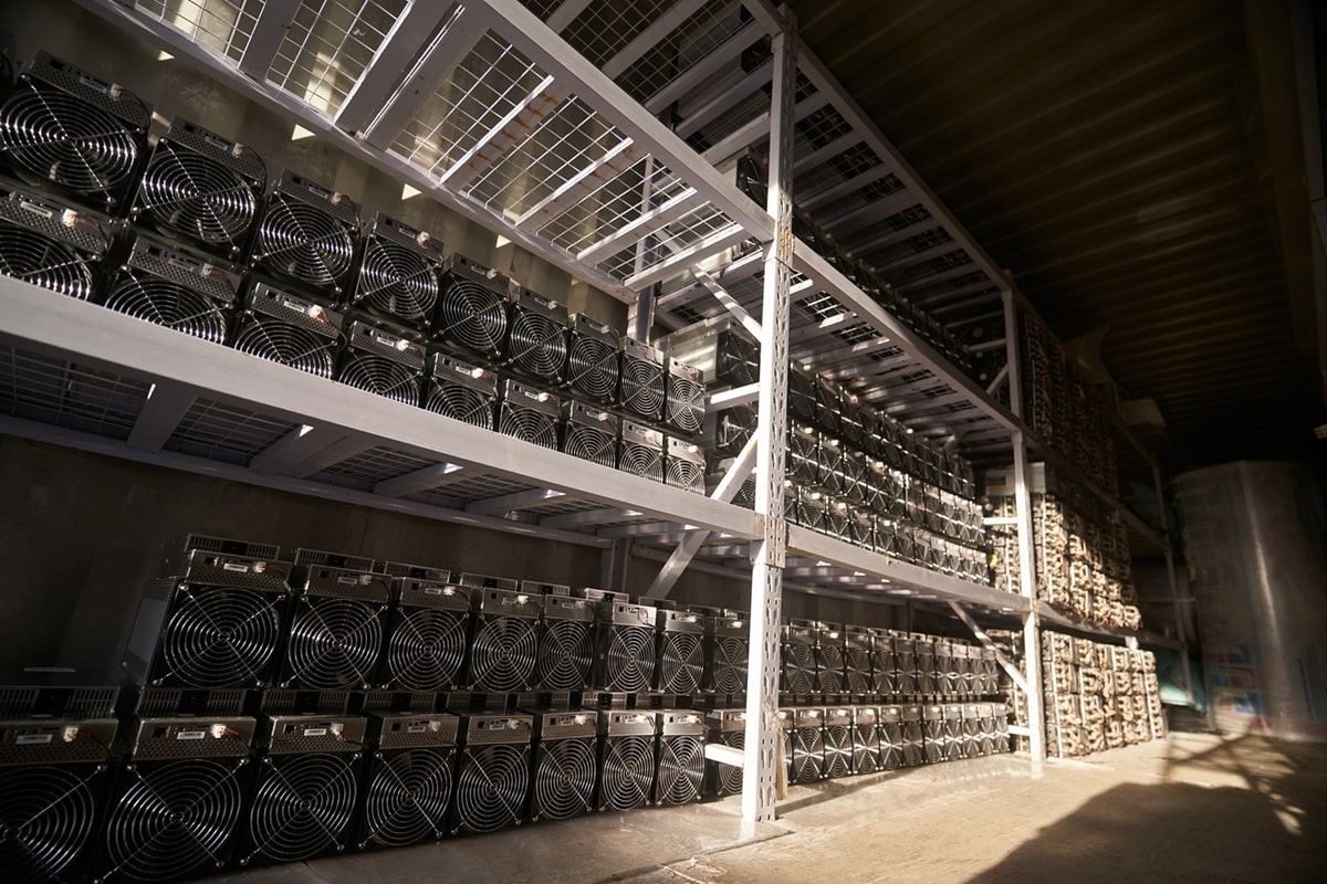 Banks of Bitcoin ASIC mining rigs in a warehouse.