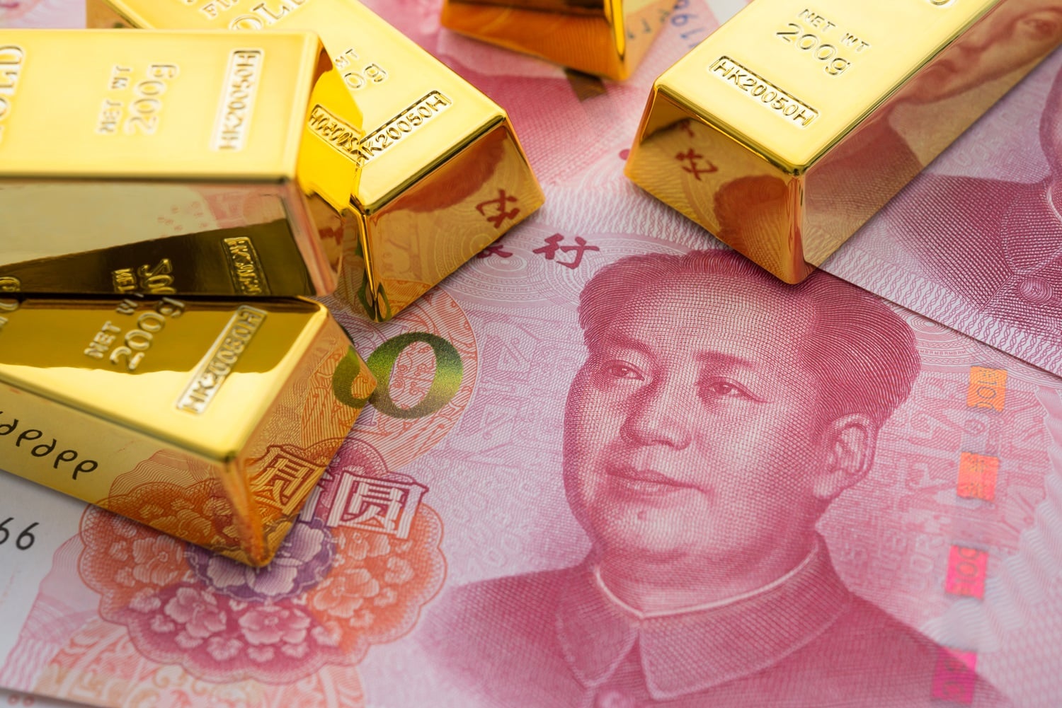 Gold bars rest on Chinese yuan banknotes.