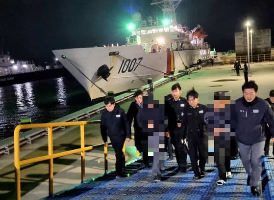 Western Regional Coast Guard officers escort two smuggling suspects off a boat in the port of Mokpo, South Korea.