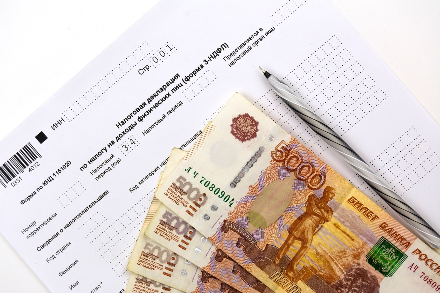 Several Russian 5000 rubles banknotes next to a pen on a tax/income declaration form.