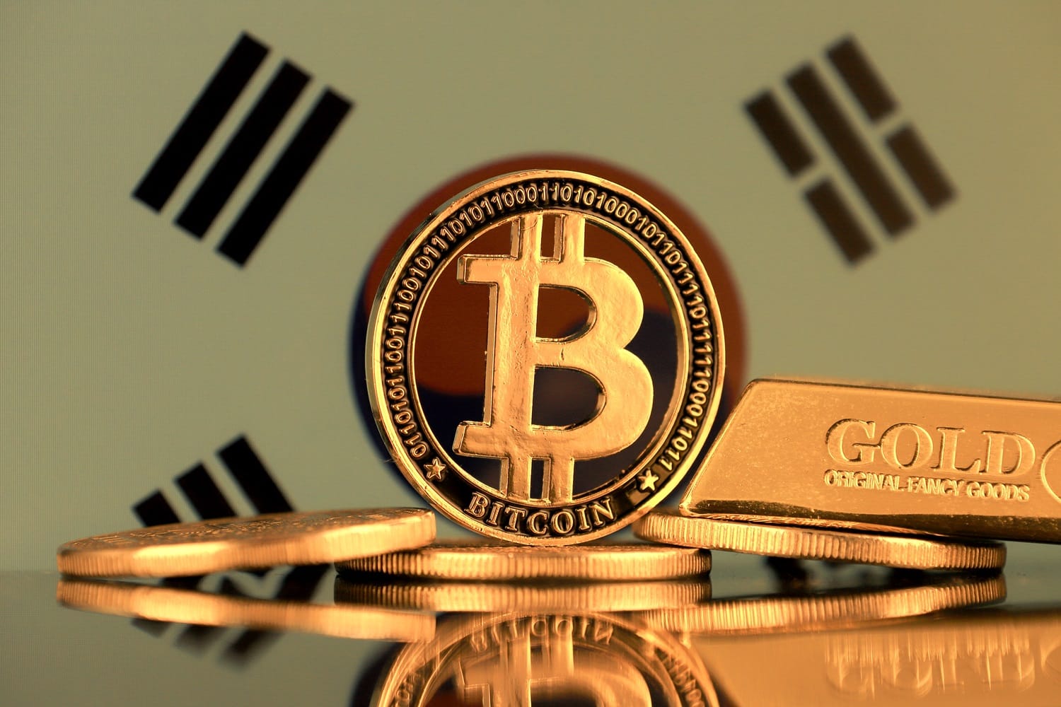 Metal coins intended to represent Bitcoin and a gold bar against the background of the South Korean flag.
