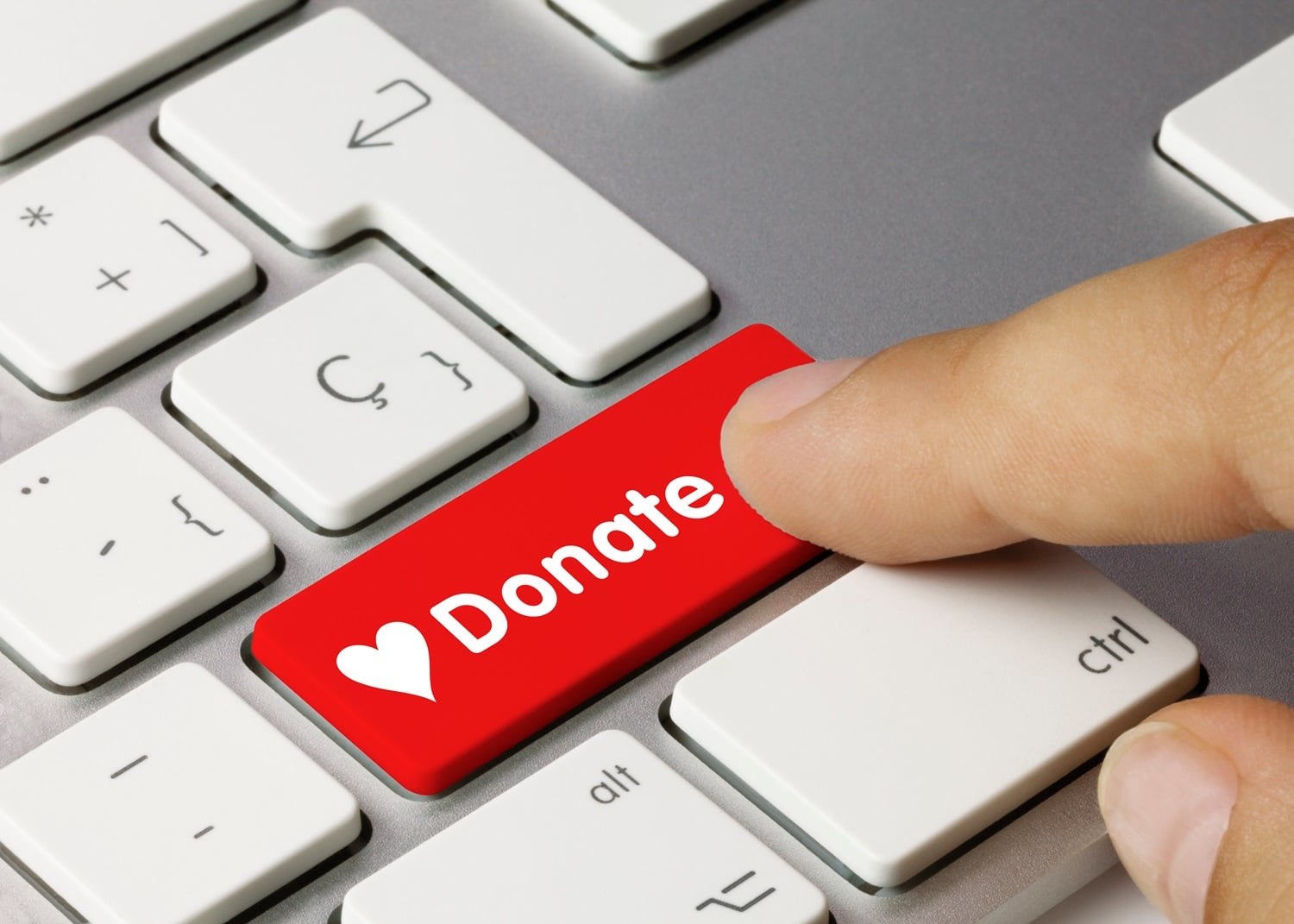 A person’s finger presses a red keyboard button labeled “donation.” Japanese Firms Collect Crypto Donations for Earthquake Victims