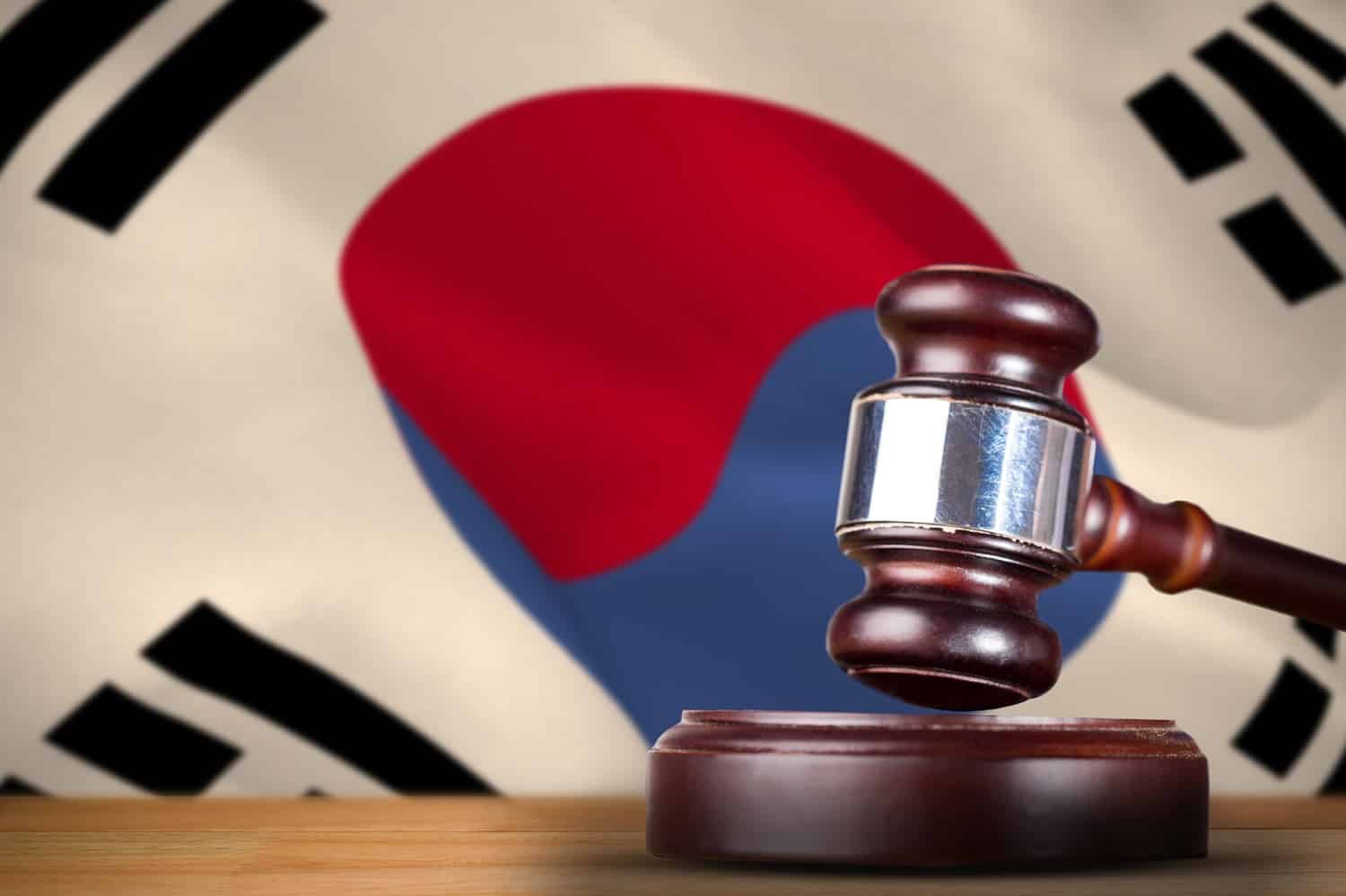 A hammer and gavel on a table in front of the South Korean flag.