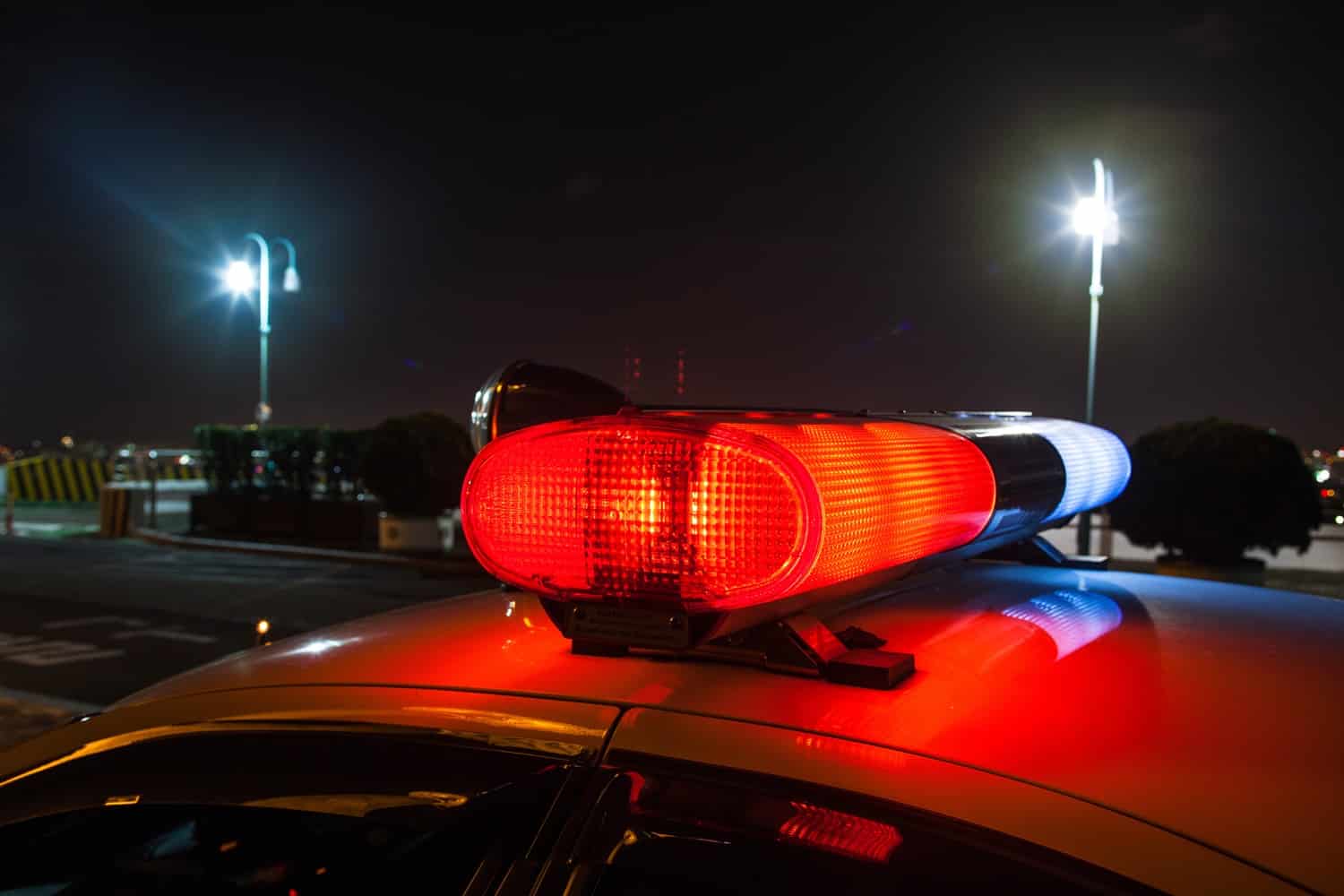 The roof of a police car at night, with its lights flashing.