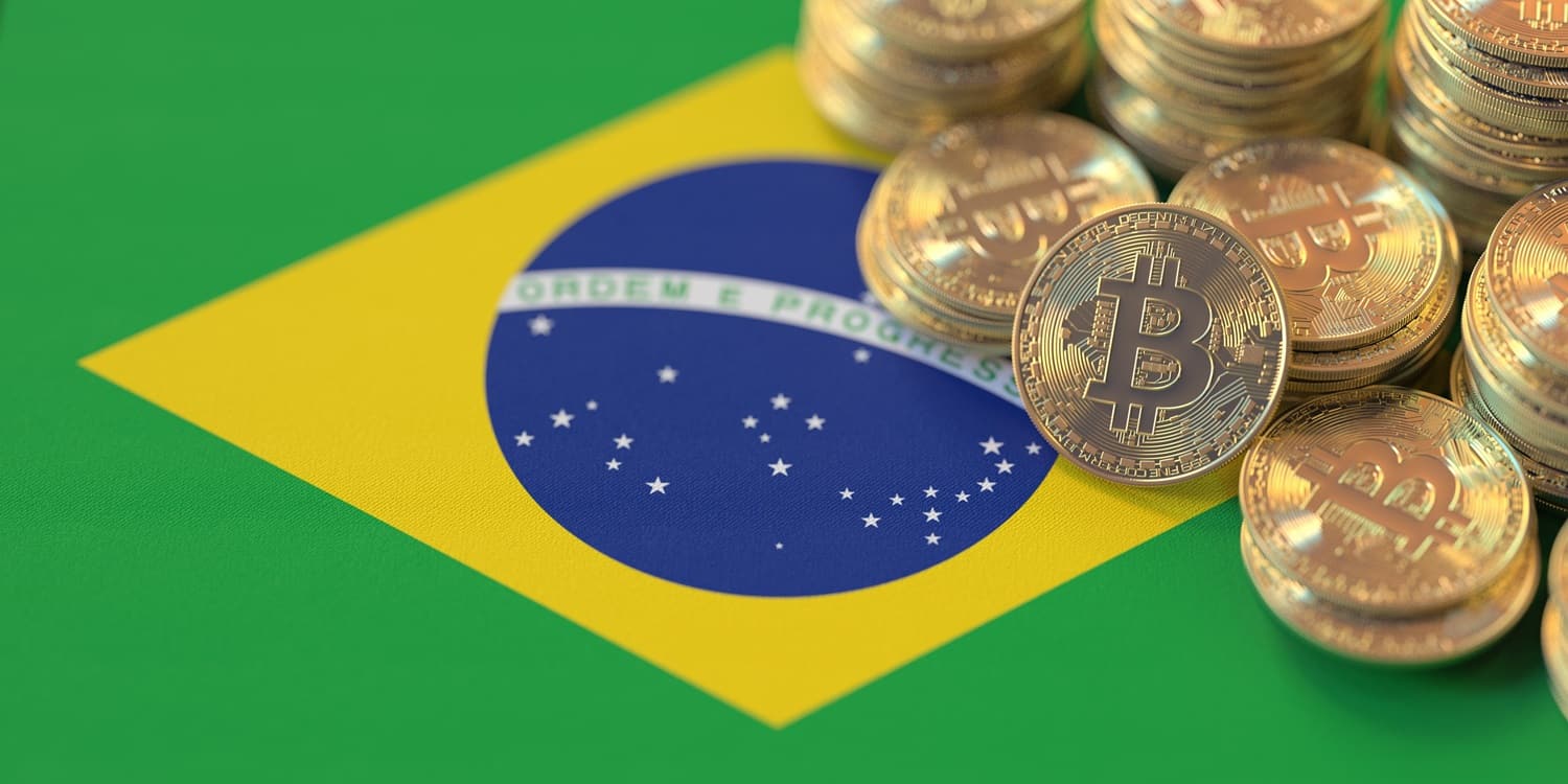 A pile of metal coins intended to represent Bitcoin on the national flag of Brazil.