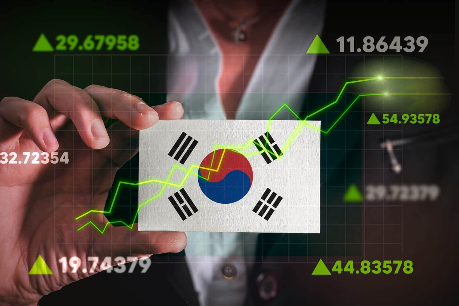 A man holds a printout of a flag of South Korea, with a stock chart and rising stock prices superimposed around the outside.