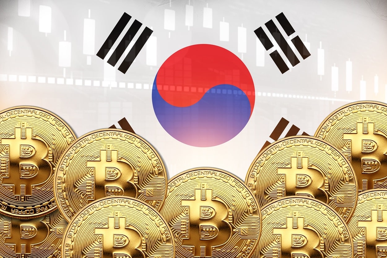 Several metal coins intended to represent Bitcoin in front of a South Korean flag, with a market chart superimposed behind.