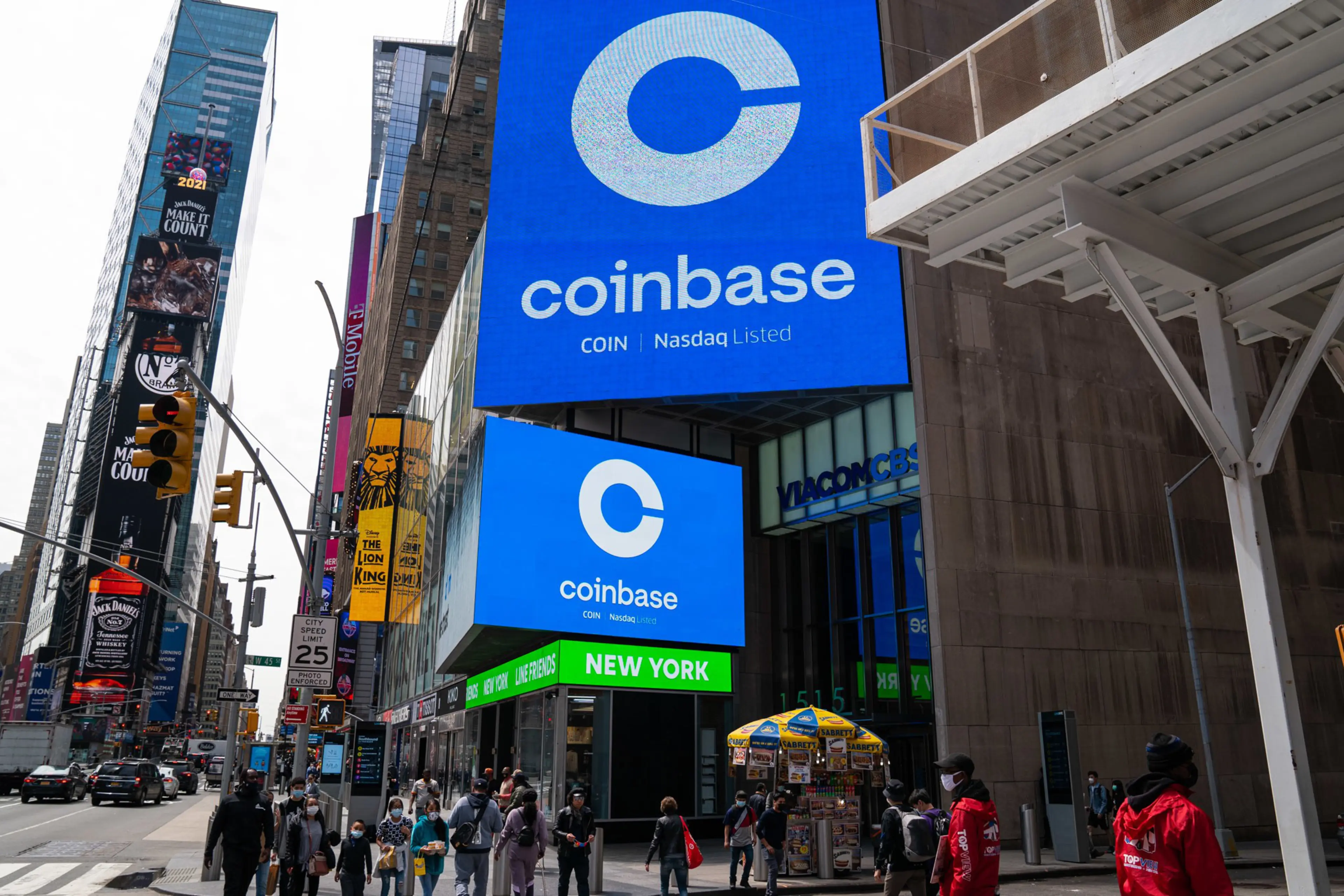 Coinbase advertising sign in Times Square, New York with pedestrians.