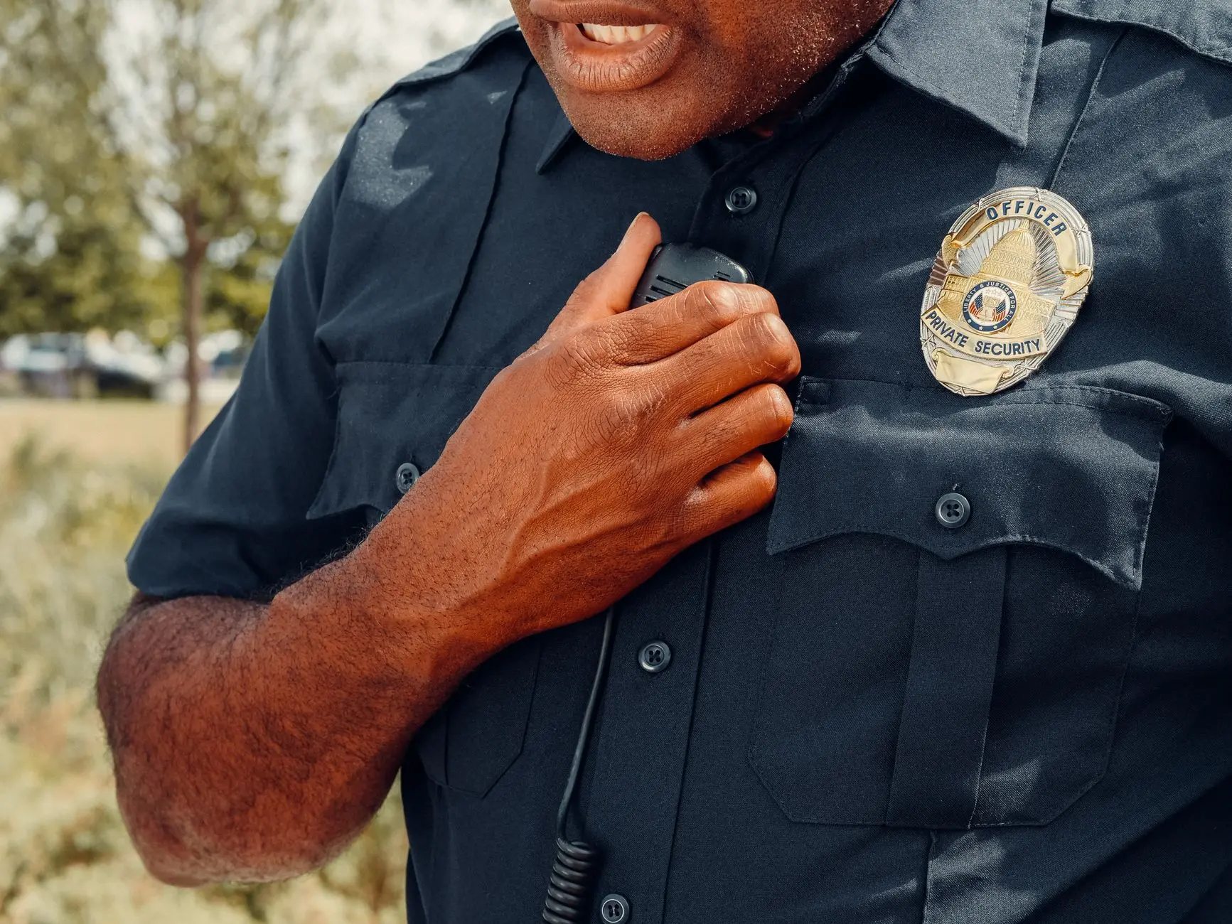 Close-up of a man's uniform with a security badge and radio.