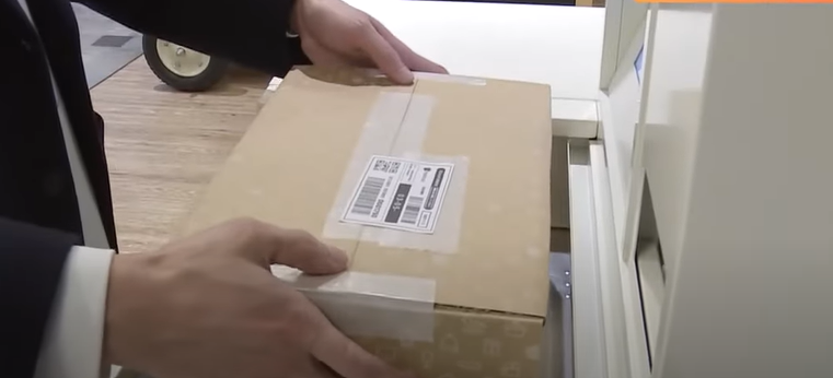 ชายคนหนึ่งใช้เครื่องส่งพัสดุอัจฉริยะเพื่อส่งพัสดุ Mercari