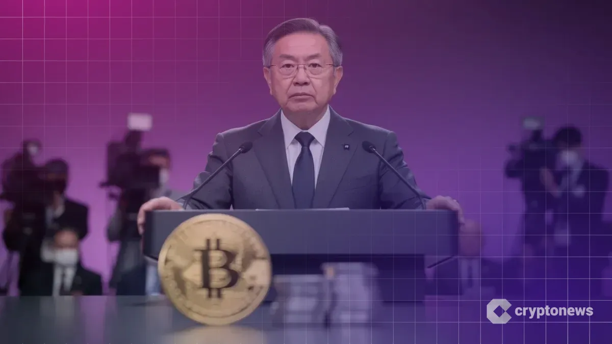記者会見で厳しい表情を見せる日銀総裁と手前にあるビットコインと円硬貨