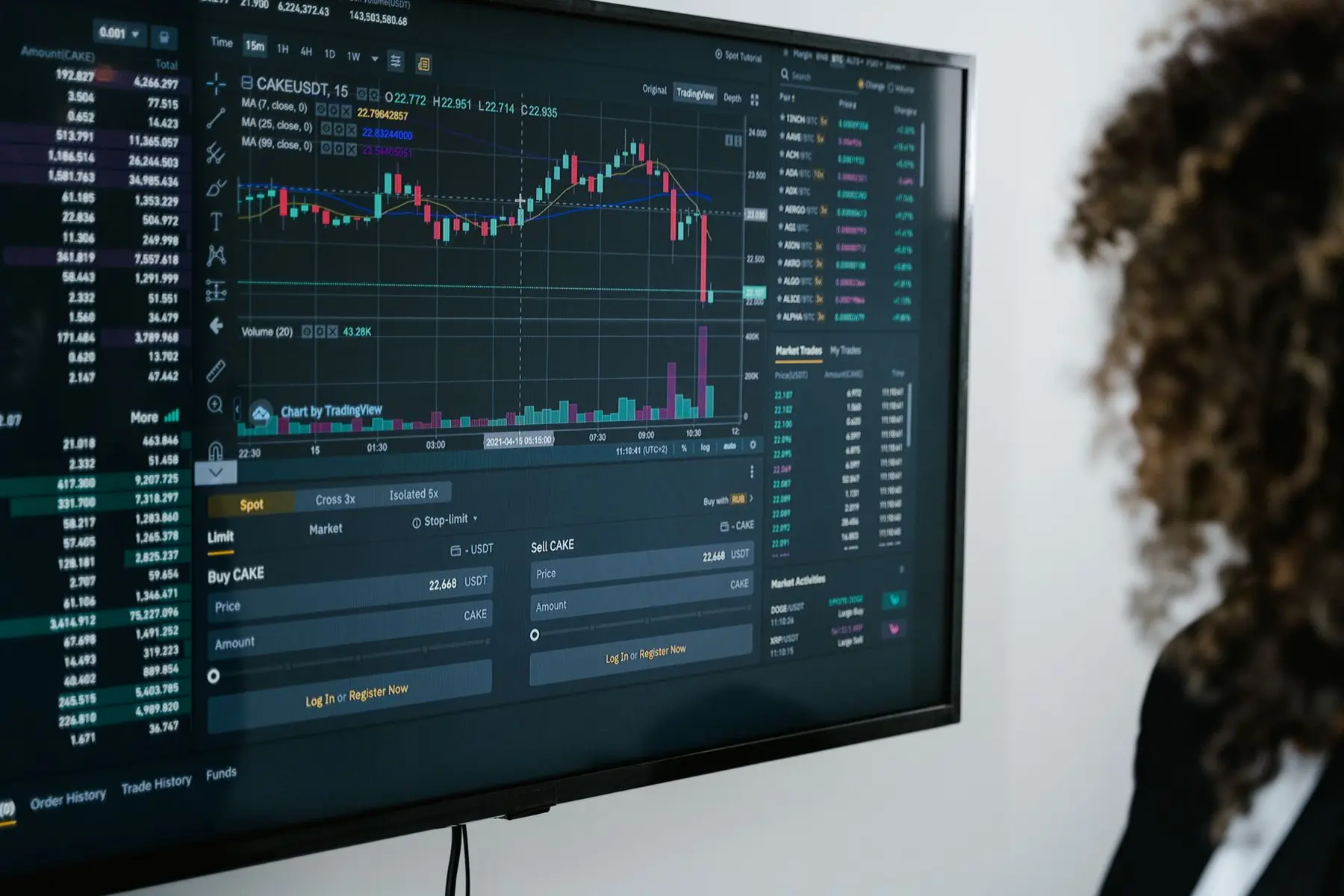 A close-up of a computer monitor displaying a cryptocurrency trading interface with candlestick charts and price data.